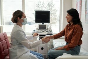 Médica e paciente conversando no consultório diante do aparelho de ultrassom