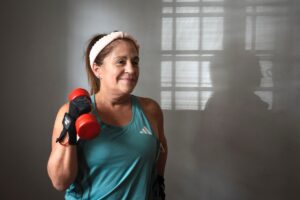 Mulher madura sorrindo enquanto faz exercício com halter, ilustrando o treino de força para emagrecer depois dos 40