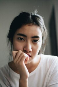 Mulher pensativa checando o celular, ilustrando a dúvida sobre menstruação atrasada